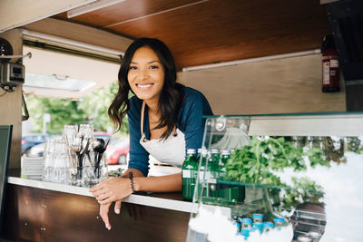 Portrait of happy female owner standing in food truck