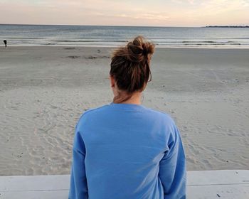 Rear view of woman standing on beach against sky