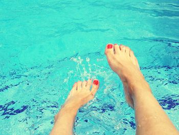 Low section of woman flapping legs on swimming pool