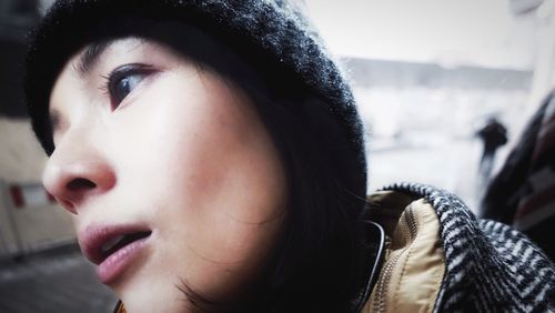 Close-up of young woman wearing knit hat in city during winter