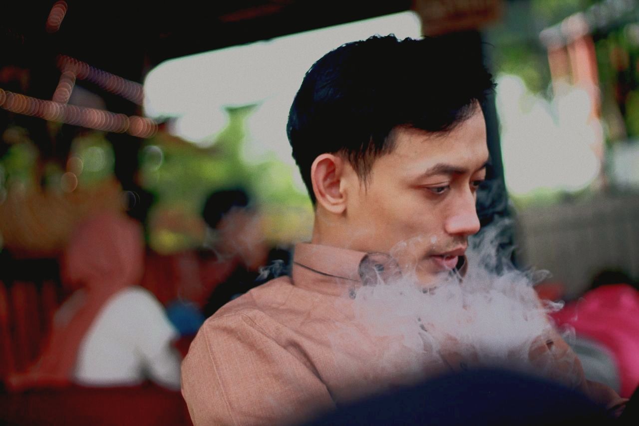 one person, adult, portrait, men, headshot, young adult, person, looking, lifestyles, focus on foreground, smoke, clothing, leisure activity, emotion, sitting, looking away, human face, outdoors