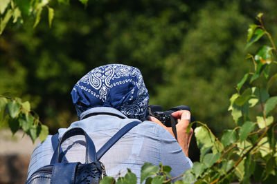 Rear view of woman photographing by plants