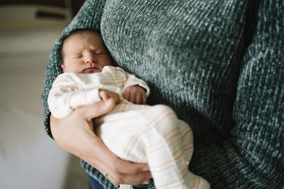 Mother carrying newborn baby boy in arms