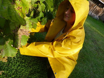 Woman in raincoat by plants on field