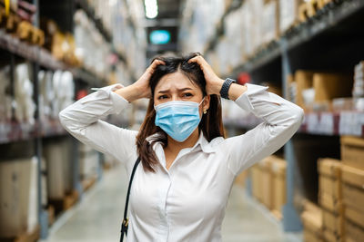 Close-up of confused woman wearing mask standing in warehouse