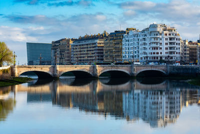 Bridge over river in city against sky