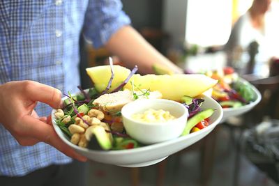 Midsection of waiter holding fresh salad plates at restaurant