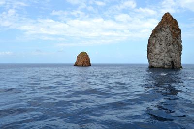 Rock formation in sea against sky