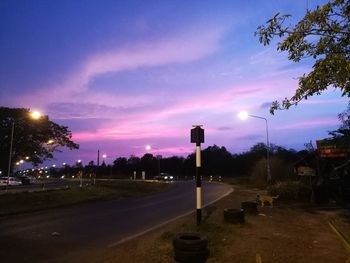 Illuminated street light against sky at sunset