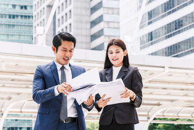 Low angle view of colleagues discussing while standing against buildings in city