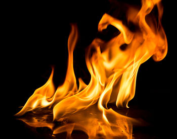 Close-up of burning candle against black background