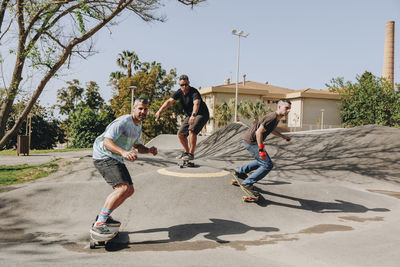 Men skateboarding at sports ramp on sunny day