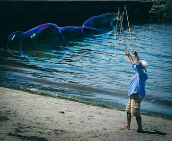 Man making large bubbles while standing at beach