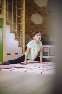 Female athlete looking away while doing stretching exercise at home