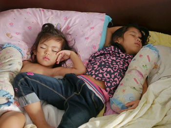 Baby girls, 2 and 4 years old, sleeping tight on a comfortable messy bed at home