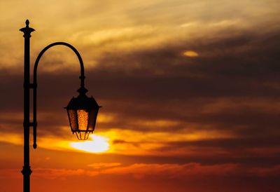 Low angle view of street light against dramatic sky