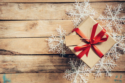 Directly above shot of christmas present and snowflakes on wooden table