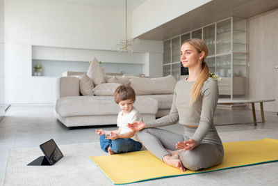 Young woman using phone while sitting on sofa at home