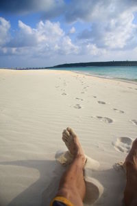 Low section of man on beach against sky