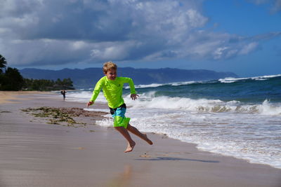 Young boy running from the waves on the beach in hawaii. 