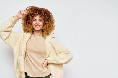 Portrait of young woman standing against white background