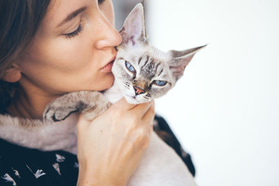 Woman kissing cat at home