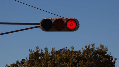 Low angle view of road signal against clear blue sky