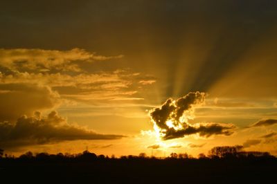 Silhouette landscape against dramatic sky during sunset