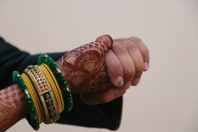 Close-up of man holding ring over white background