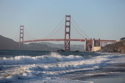 Suspension bridge over sea against clear sky