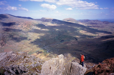 Hiker standing on rock formation at snowdonia national park against sky