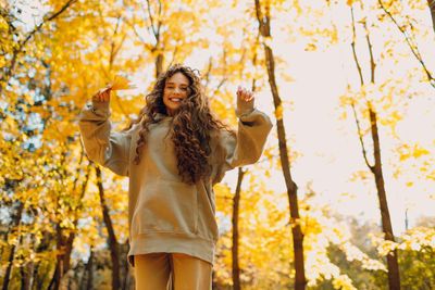 Young woman standing against trees