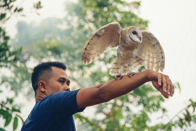 Close-up of man holding owl on hand
