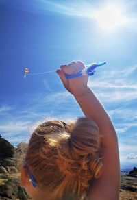 Close-up of girl flying kite at beach against blue sky