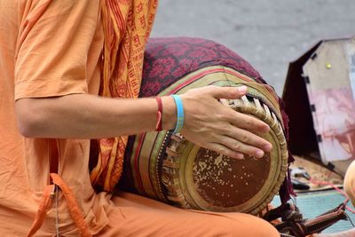 Midsection of man wearing traditional clothes banging drum outdoors