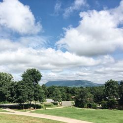 High angle view of footpath in trees and mountains against cloudy sky