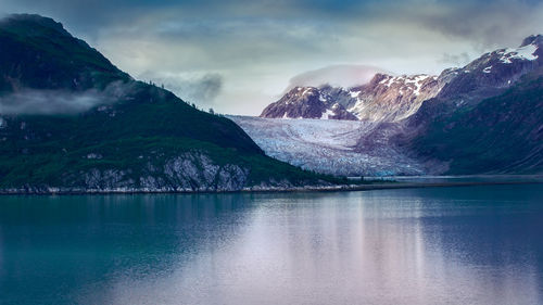 Scenic view of lake by snowcapped mountains against sky