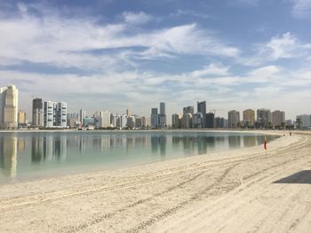 Sea by modern buildings against sky in city