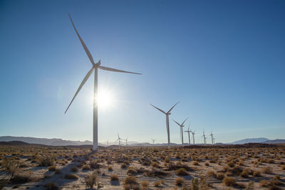 Wind turbines on field against clear sky