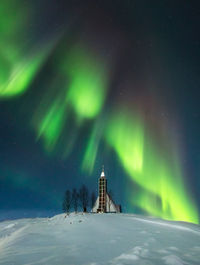 Built structure on snow covered land against sky at night