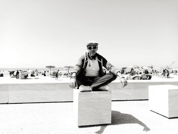 Portrait of young man sitting against sky