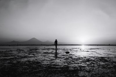 Silhouette man standing on beach against clear sky