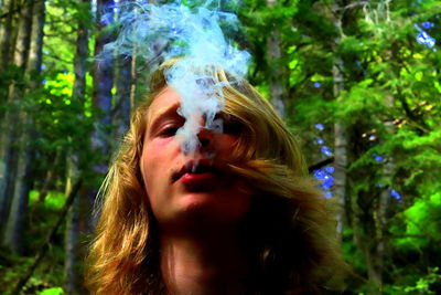 Portrait of young woman smoking in forest