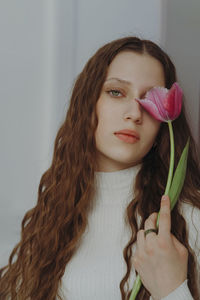 Portrait of a young girl with long hair and a tulip flower