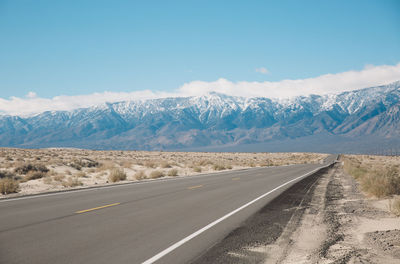 Road by mountains against sky during winter