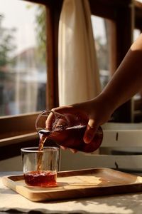 Midsection of woman holding coffee on table