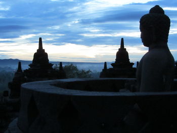 Silhouette of temple against cloudy sky