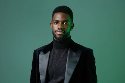 Portrait of young man standing against black background