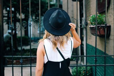 Rear view of woman with hat by iron fence