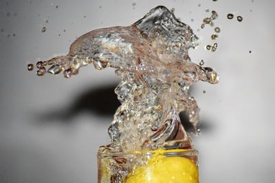 Close-up of water splashing in glass with lemon